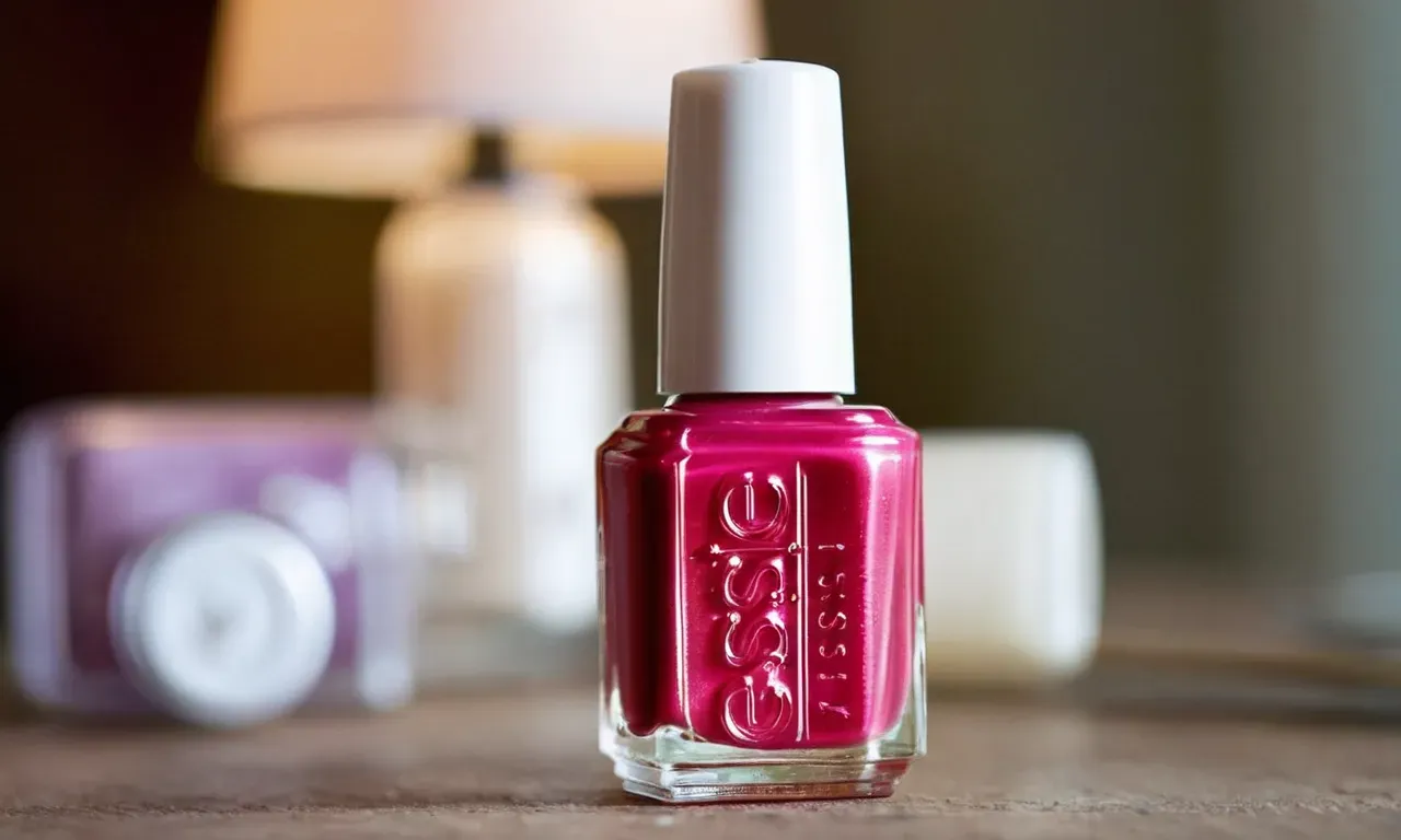 Close-up shot of a freshly painted Essie nail polish bottle, surrounded by a blurred background of a timer ticking away, symbolizing the curiosity of "how long does Essie nail polish take to dry."