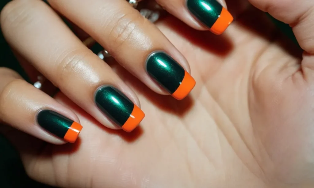 A close-up shot of a hand adorned with dark green and orange nail polish, creating a striking contrast against the skin, capturing a bold and vibrant manicure.